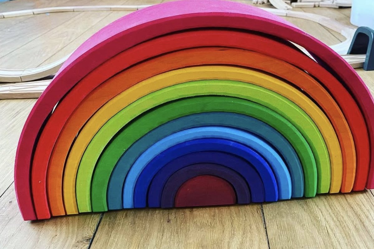 Un arcobaleno di legno a incastro con archi colorati, appoggiato su un parquet